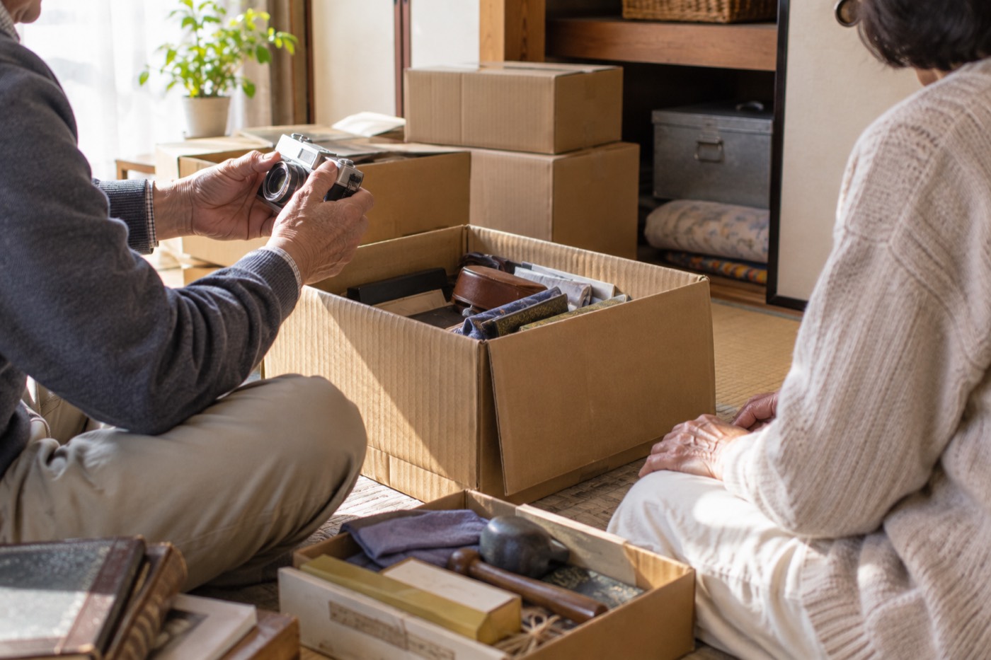 押し入れの前で古い箱を開ける夫婦の手元