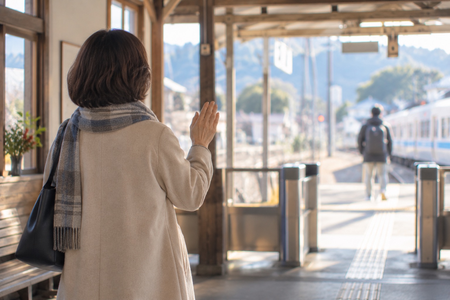 駅の改札で手を振って見送る女性の後ろ姿
